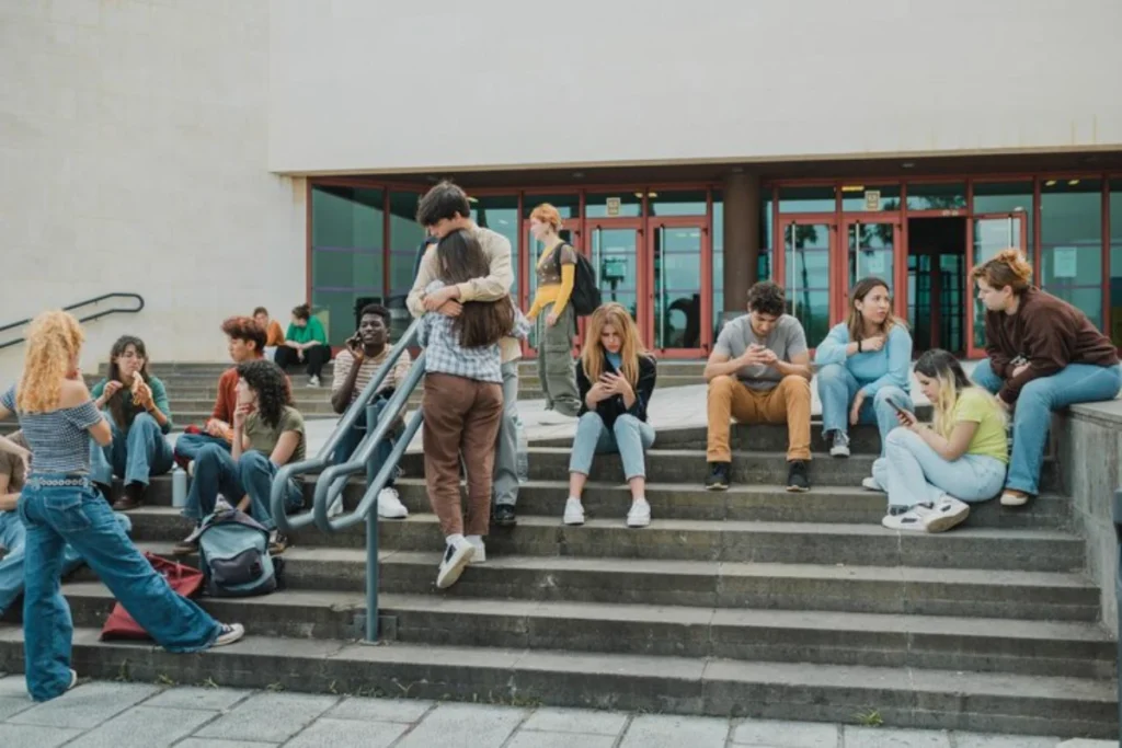 Group of friends sitting on stairs against highschool building