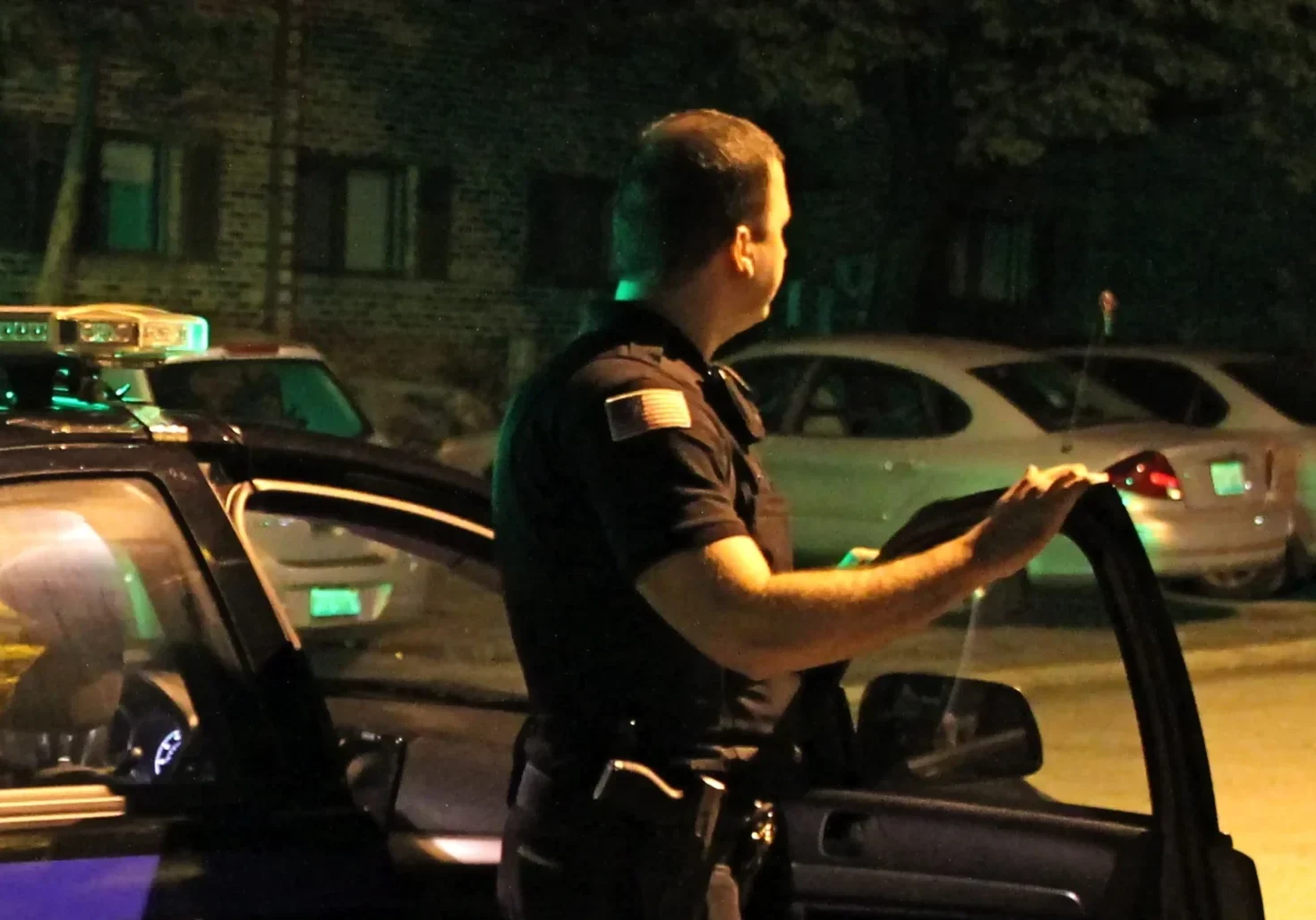 emergency-staffing-chicago-illinois-60656 Armed security officer standing beside a patrol vehicle at night during an active response