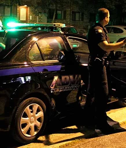 residential-security-services-chicago-illinois-60656 Alarm response officer outside a patrol car with emergency lights during a nighttime residential check in Chicago, IL-60656