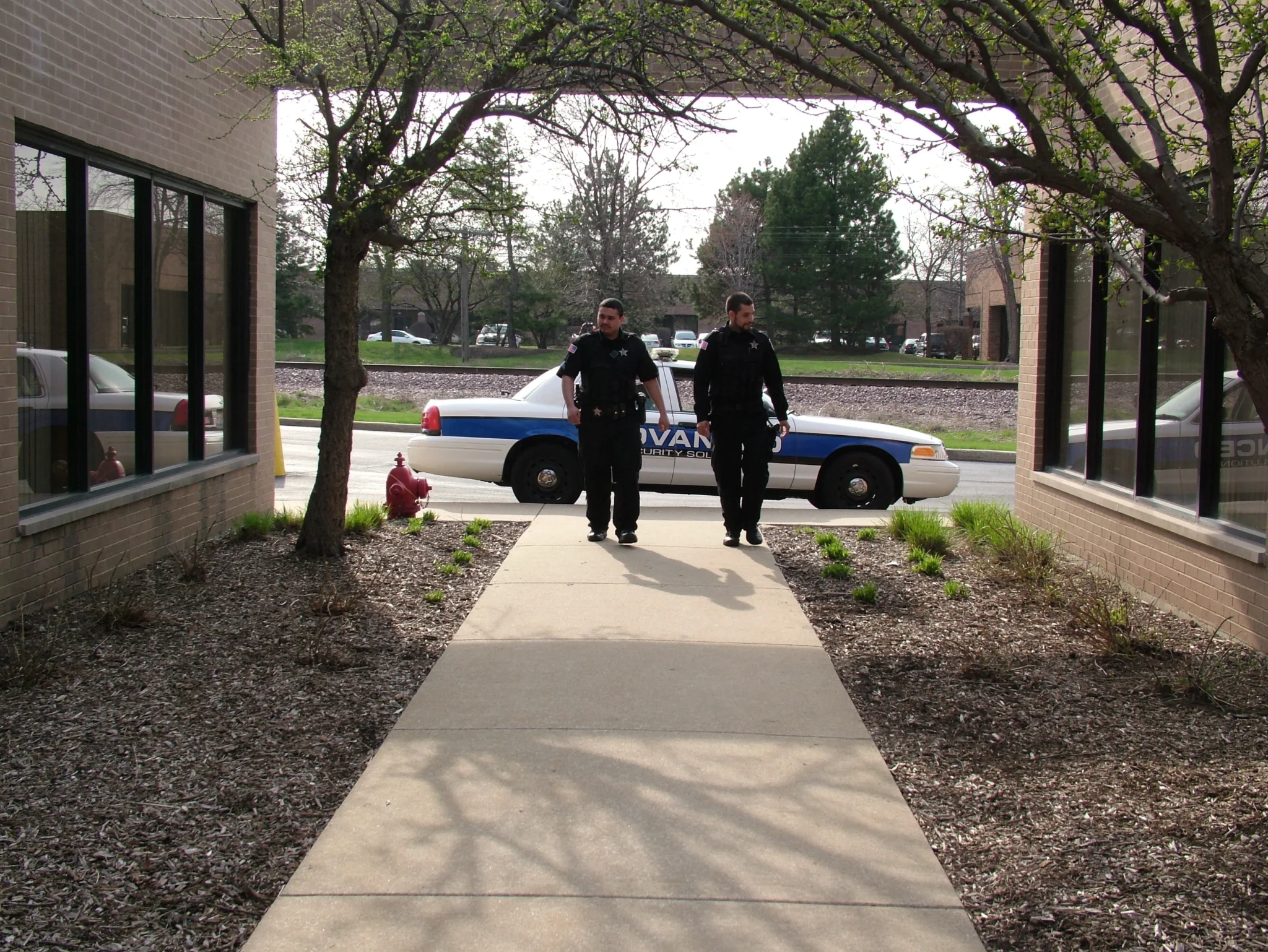 Mobile patrol security officers walking a property perimeter with patrol vehicle on site for residential property security in Chicago